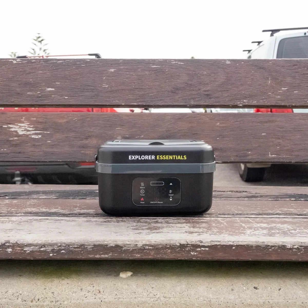 Explorer Essentials heated lunchbox on a bench beside a ute